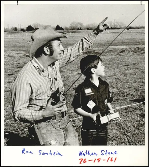 An Instructor points skyward while a young student holds the transmitter
